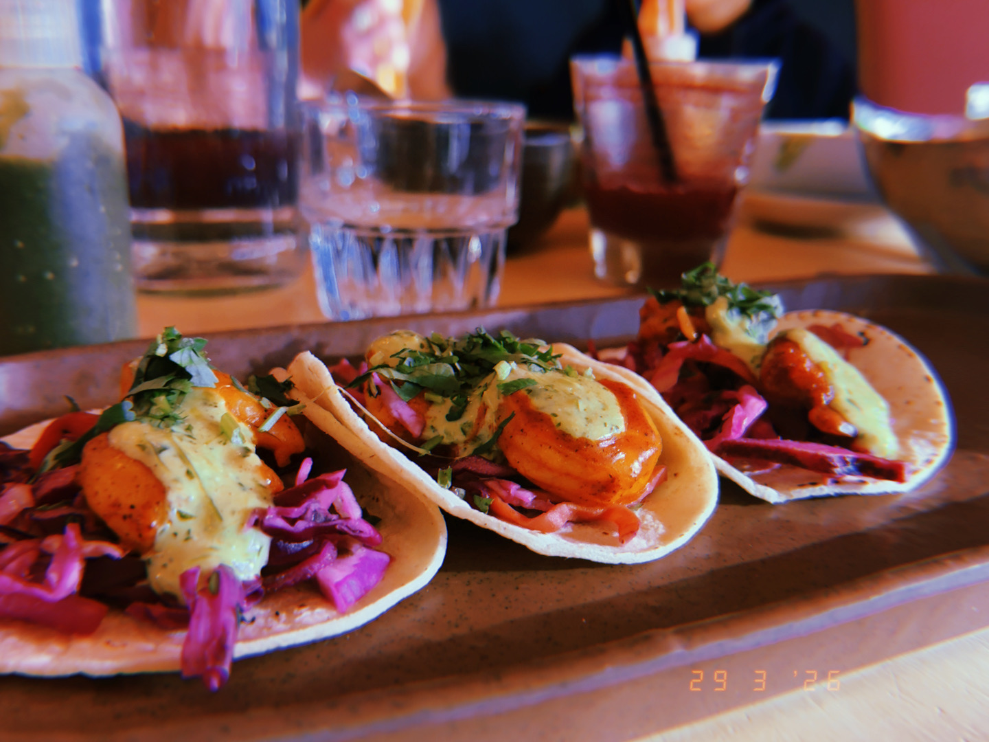 Three shrimp tacos on purple cabbage slaw with creamy sauce and cilantro